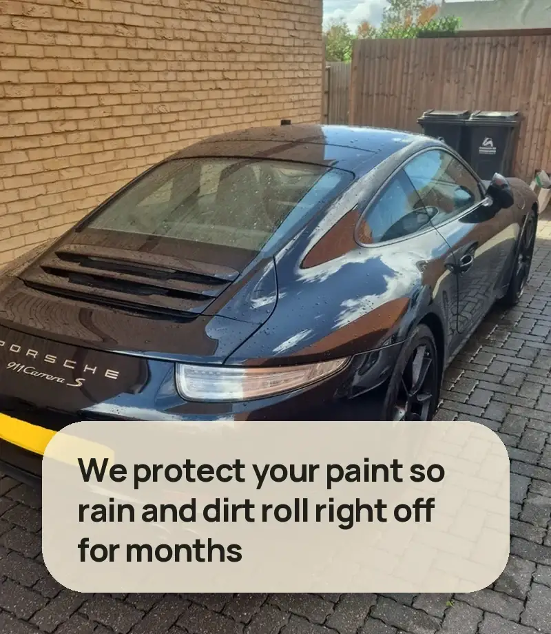 We protect your paint so rain and dirt roll right off for months - glossy black Porsche 911 Carrera S with the sky reflected in the paint